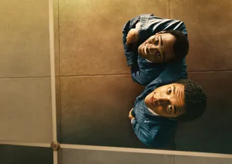 Leads of Nickel Boys looking upwards into a mirror.